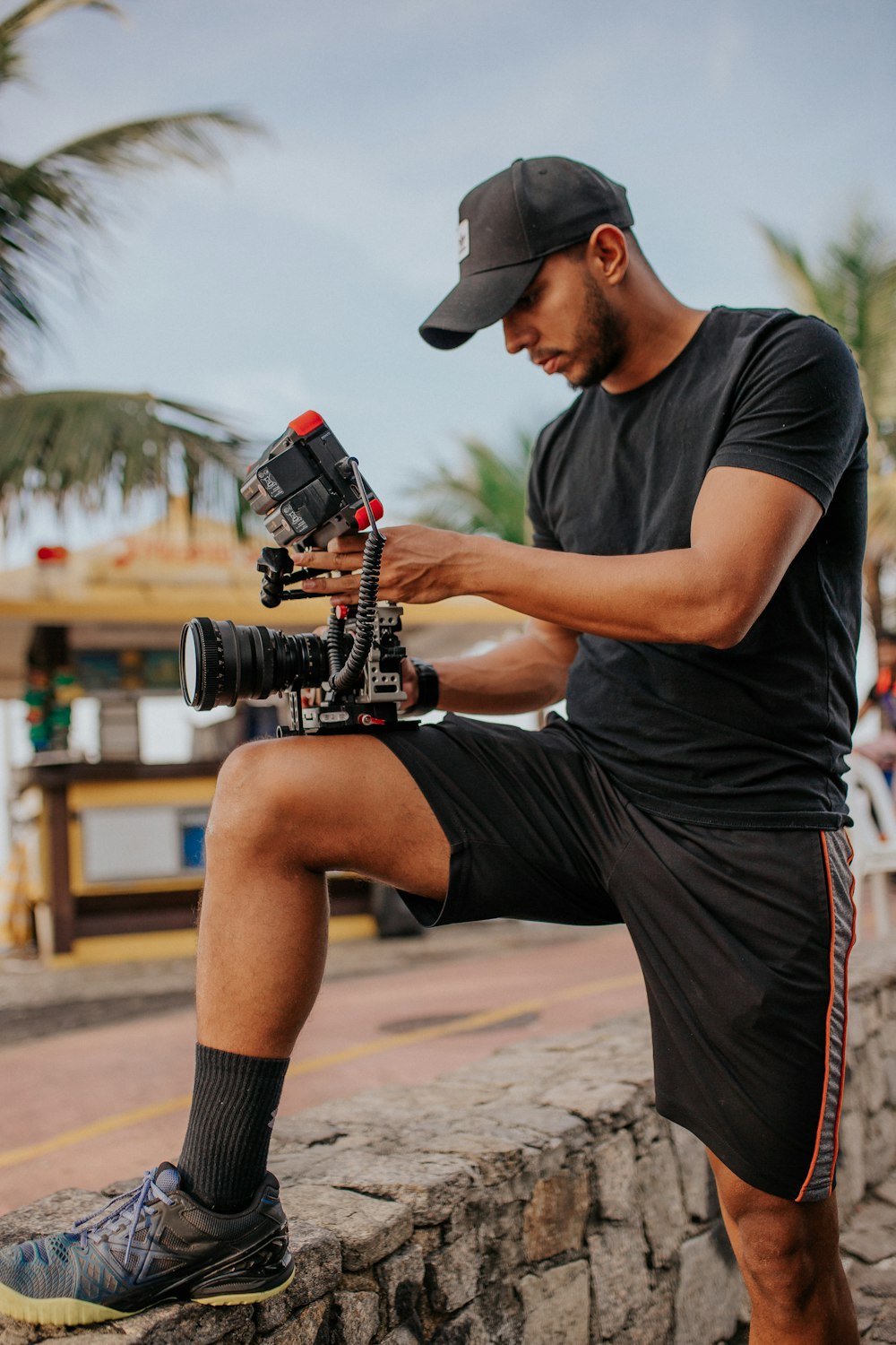 man in black t-shirt and brown shorts sitting on brown wooden bench during daytime