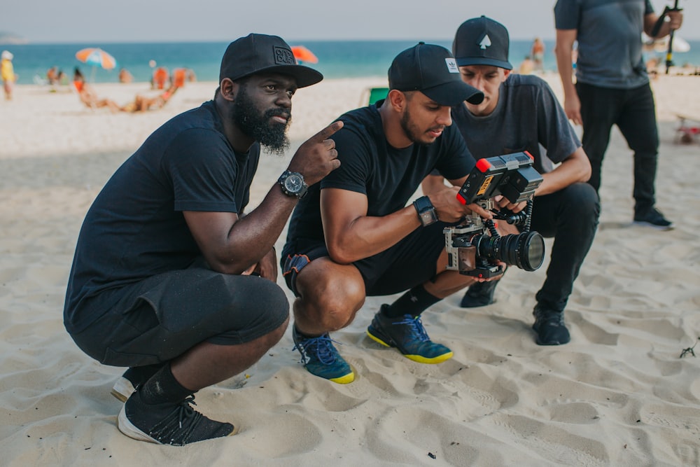 man in black t-shirt and blue shorts sitting on sand