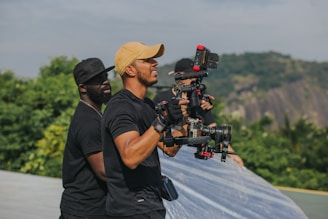 man in black t-shirt and brown hat holding black dslr camera