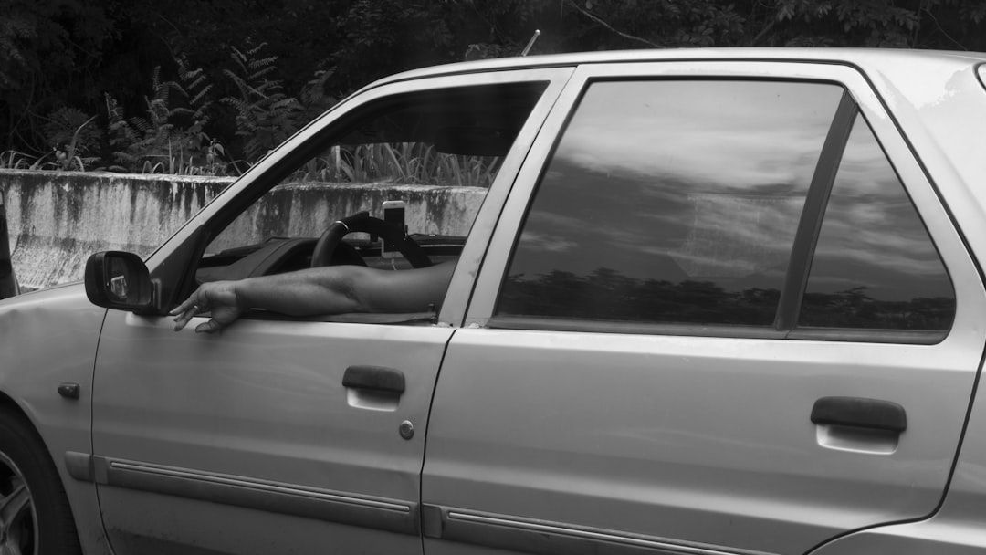 grayscale photo of man driving car