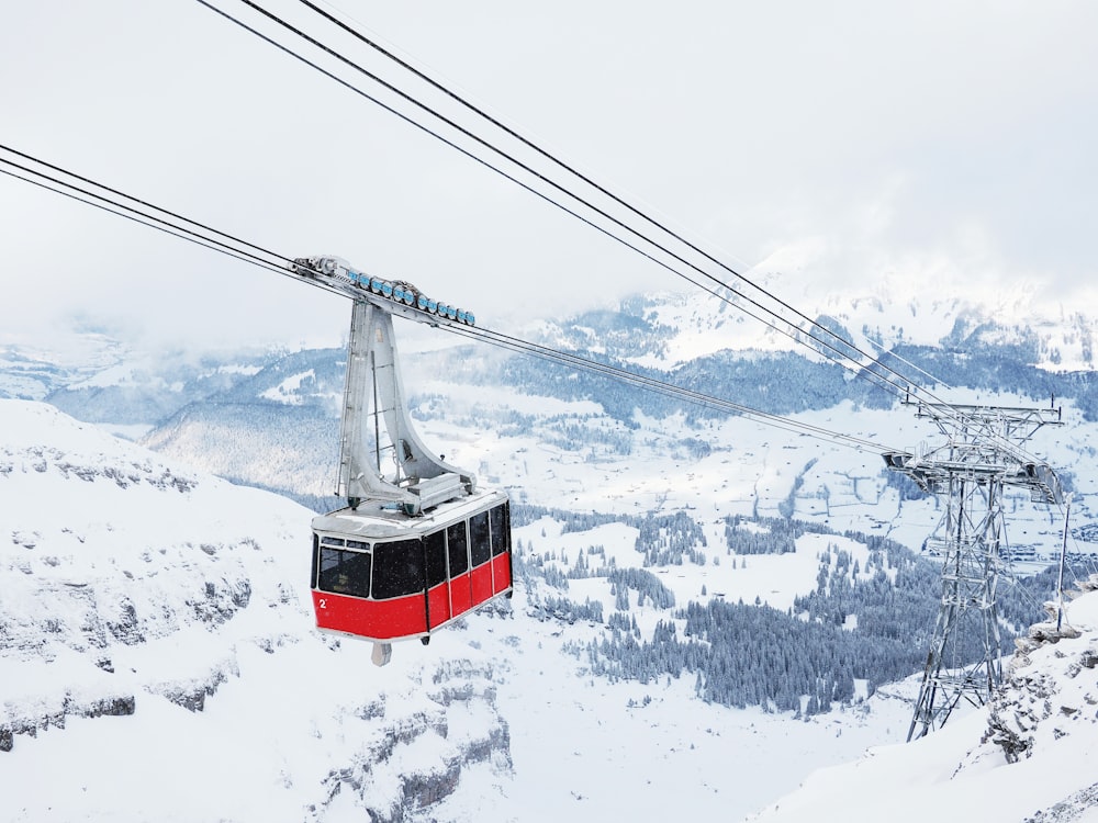 Teleférico rojo sobre la montaña cubierta de nieve durante el día