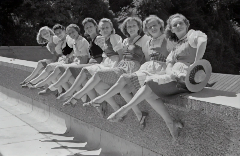 black and white photo of women sitting on a concrete bench