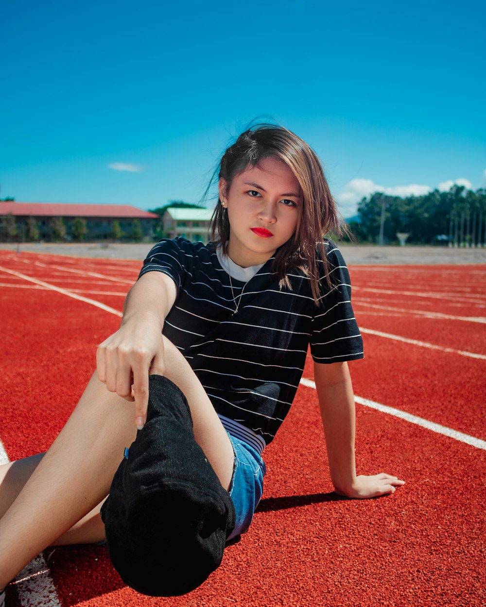 girl in black and white striped shirt sitting on red and white concrete floor during daytime