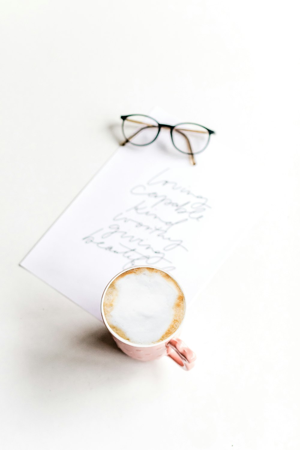 white ceramic mug with coffee on white paper