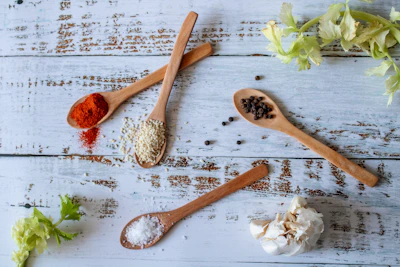 A set of wooden kitchen spoons resting beside fresh herbs on a rustic countertop.