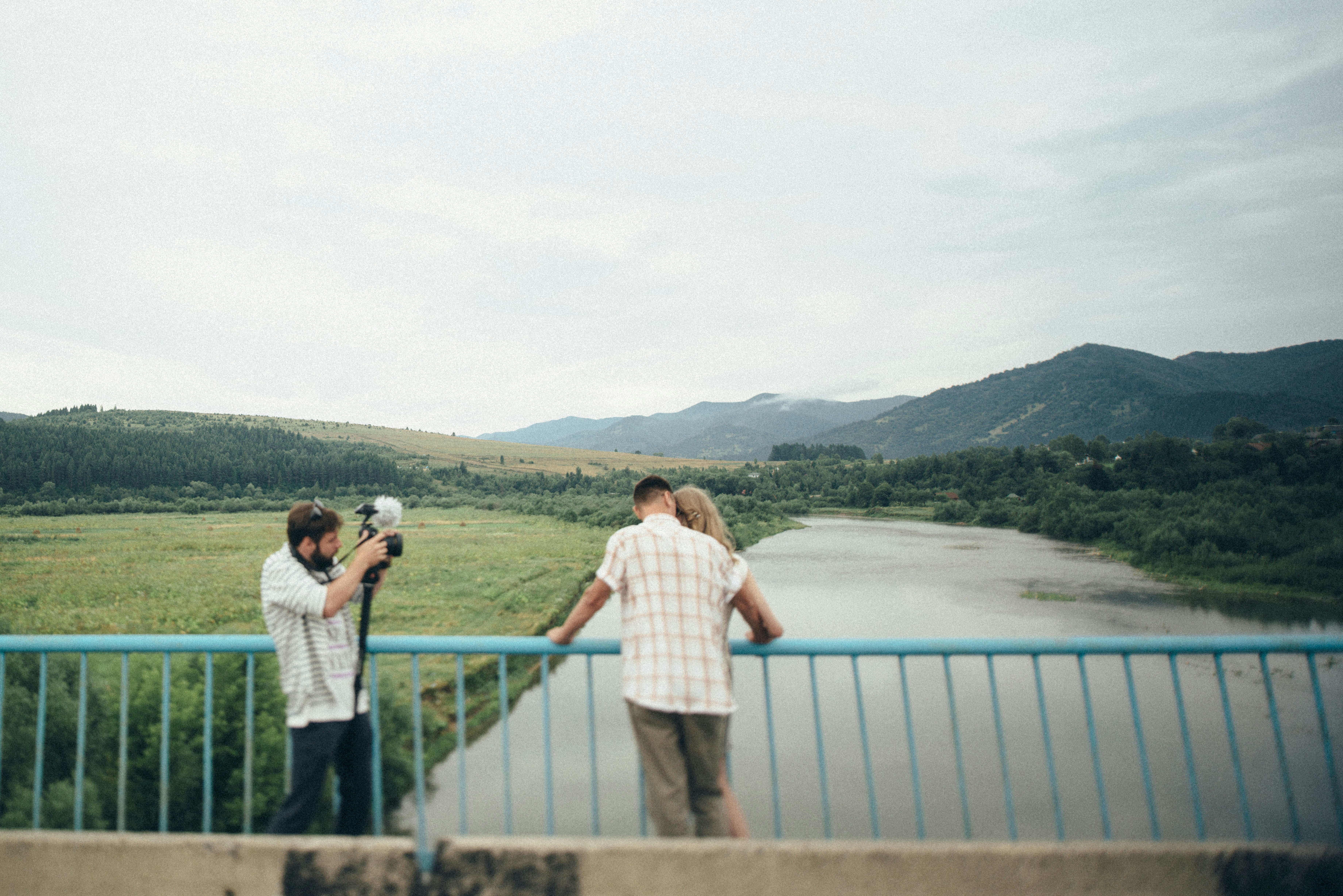 Couple standing on gray metal railings near body of water during ...