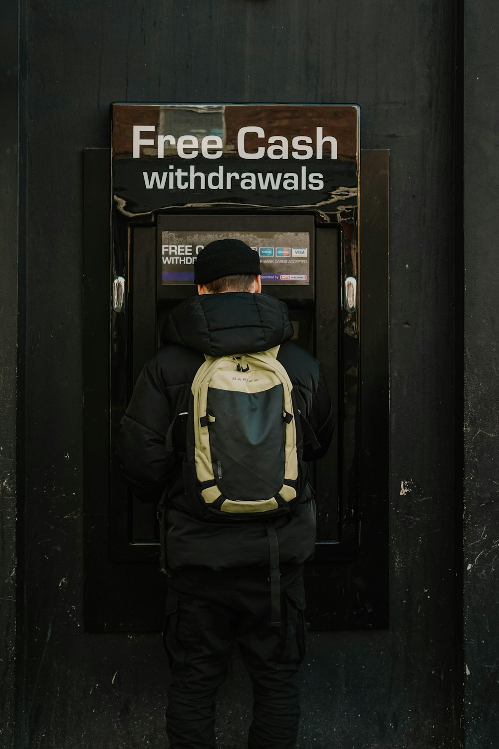 man in blue and yellow jacket and black backpack standing in front of brown wooden door