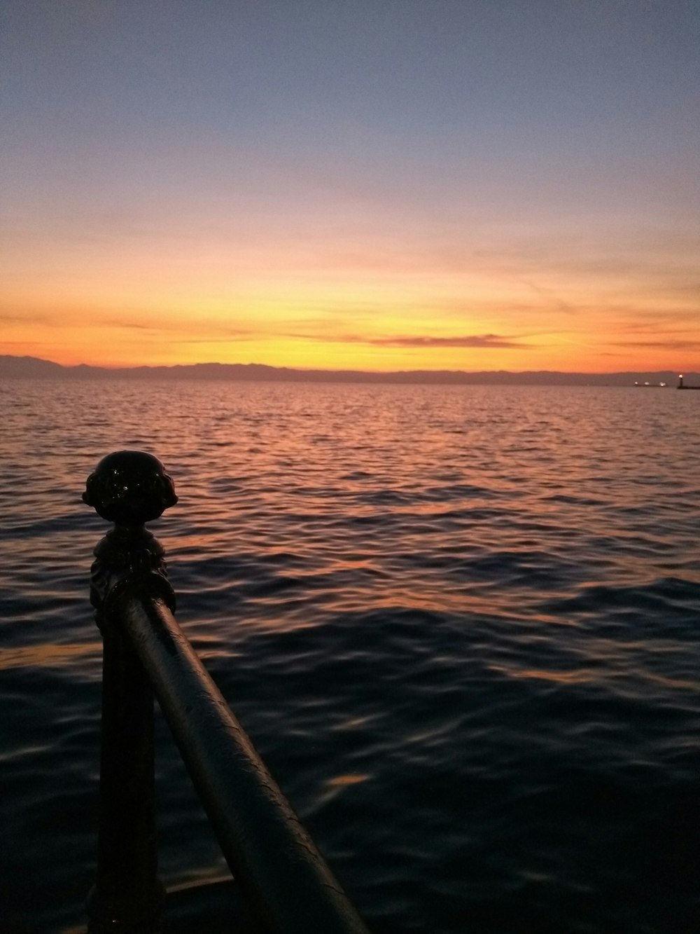 silhouette of person standing on sea dock during sunset