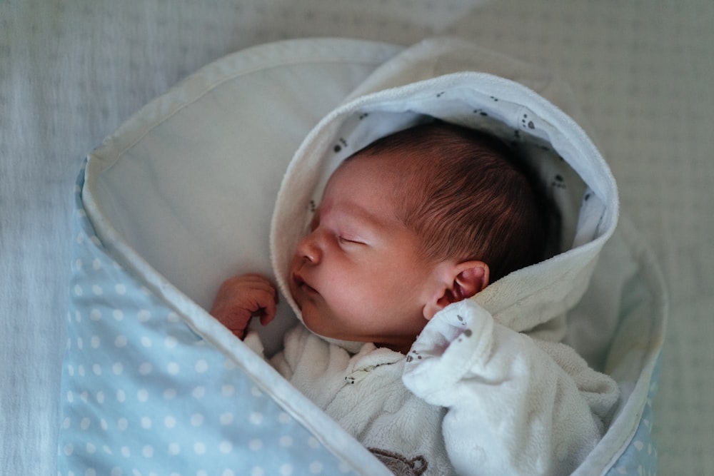 baby in white and gray blanket