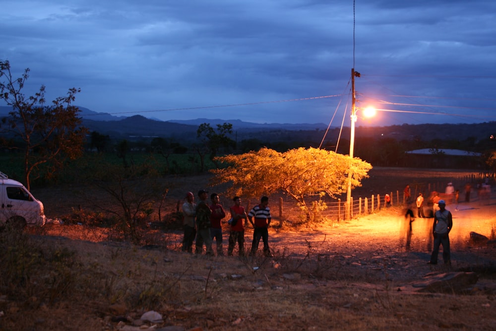 pessoas em pé no campo marrom durante o pôr do sol