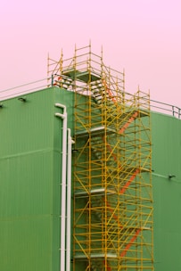 white metal ladder beside green wall
