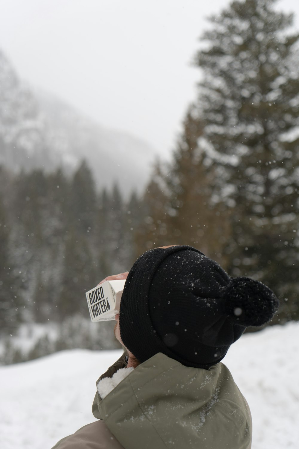 person in black knit cap holding red and white card