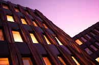 Contemporary mixed-use development with dark charcoal facade and gold detailing under a twilight sky.