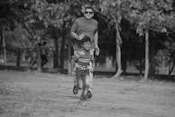 A candid black-and-white shot of a family laughing together in a park.