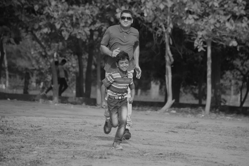 A warm, sunlit photo of two children happily playing together in a park, symbolizing harmony between co-parents.