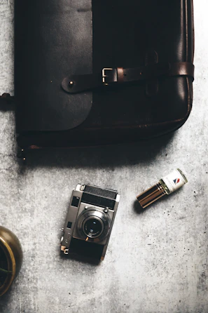 A moody flat lay featuring open perfume boxes, scent notes, and a vintage fragrance vial on a charcoal surface.