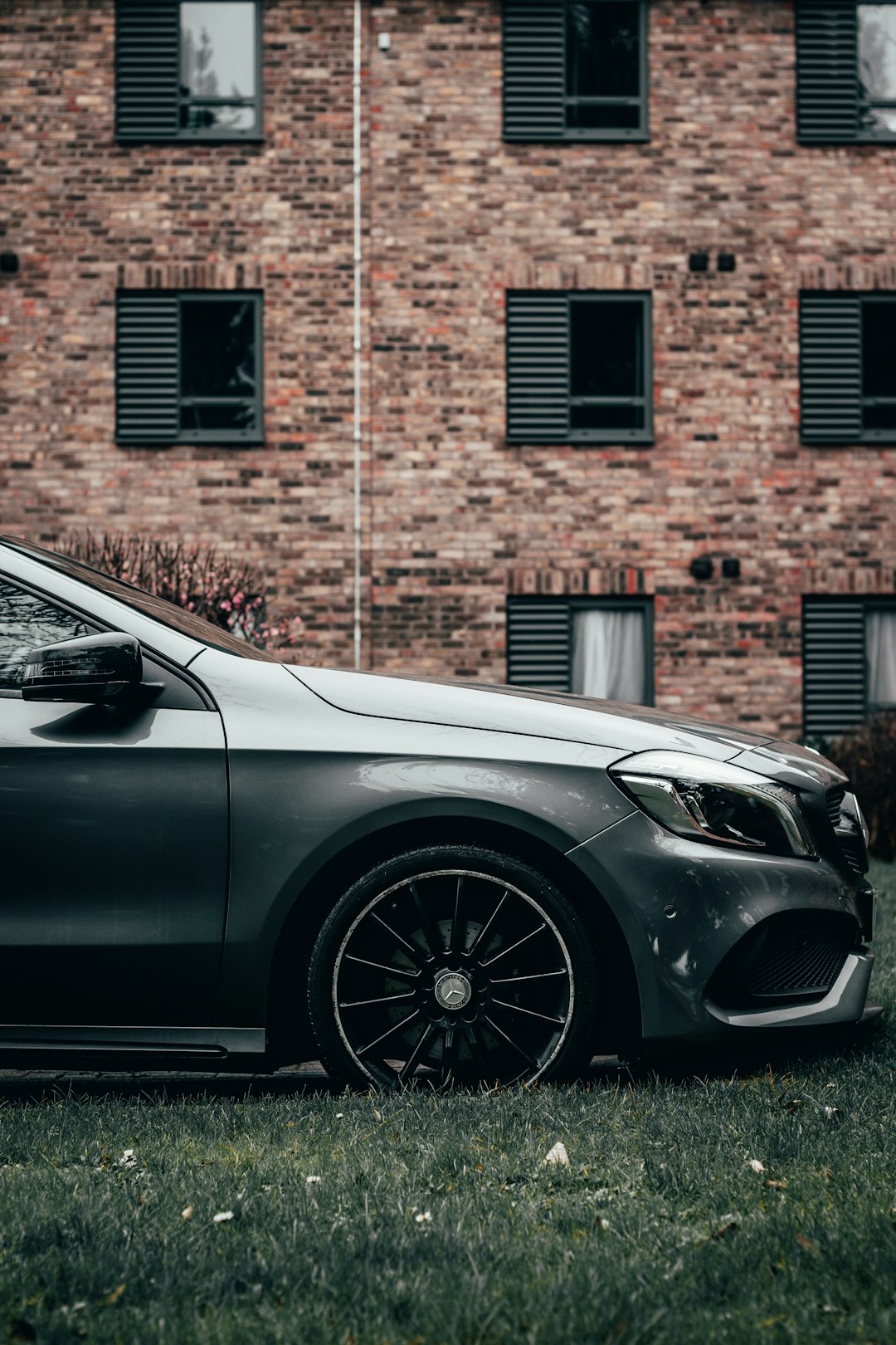 silver car parked beside brown brick wall