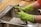 A person wearing bright green rubber gloves is washing a kitchen tap over a stainless steel sink. The setting appears to be a domestic kitchen with a wooden countertop.