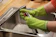 A close-up of a gloved hand wiping grease off a spotless oven glass door in a bright modern kitchen.