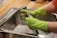 A plumber repairing a residential sink with professional tools in a bright kitchen.