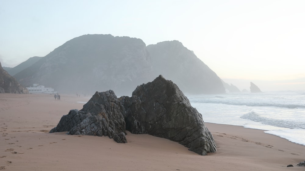 Formación rocosa marrón en la playa durante el día