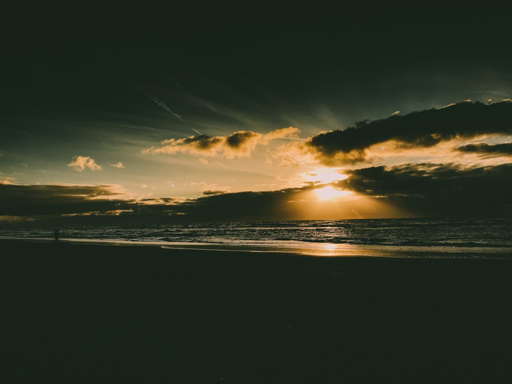 body of water under cloudy sky during sunset