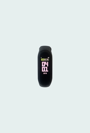 A sleek, black fitness tracker displays the date and time on its screen, with numbers in pink and information in light green and white. It is centered on a plain, light gray background.