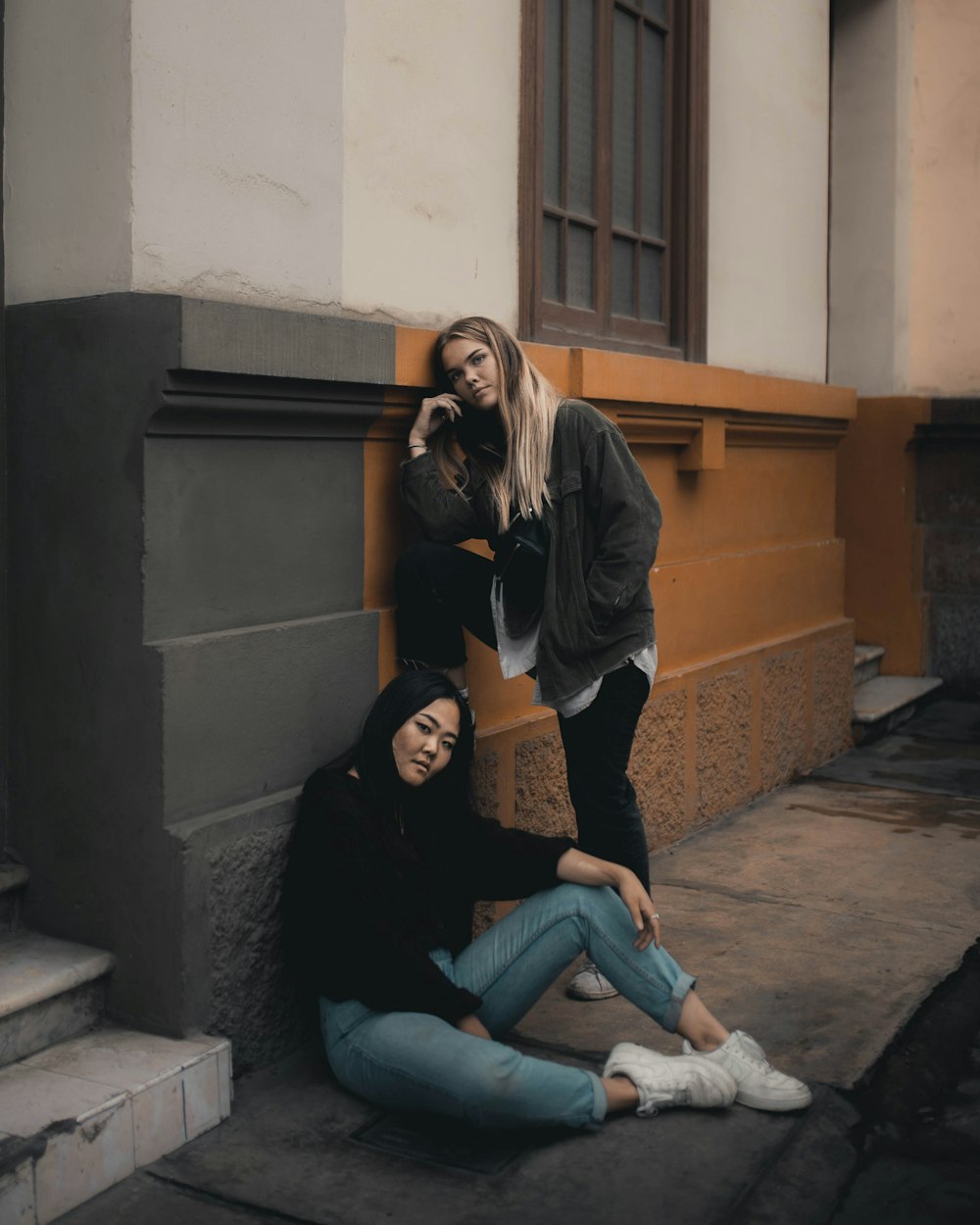 woman in brown long sleeve shirt and blue denim jeans sitting on concrete stairs