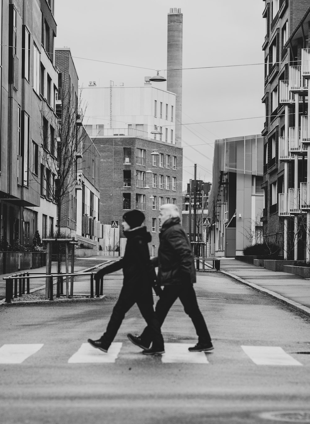 man in black jacket walking on sidewalk in grayscale photography