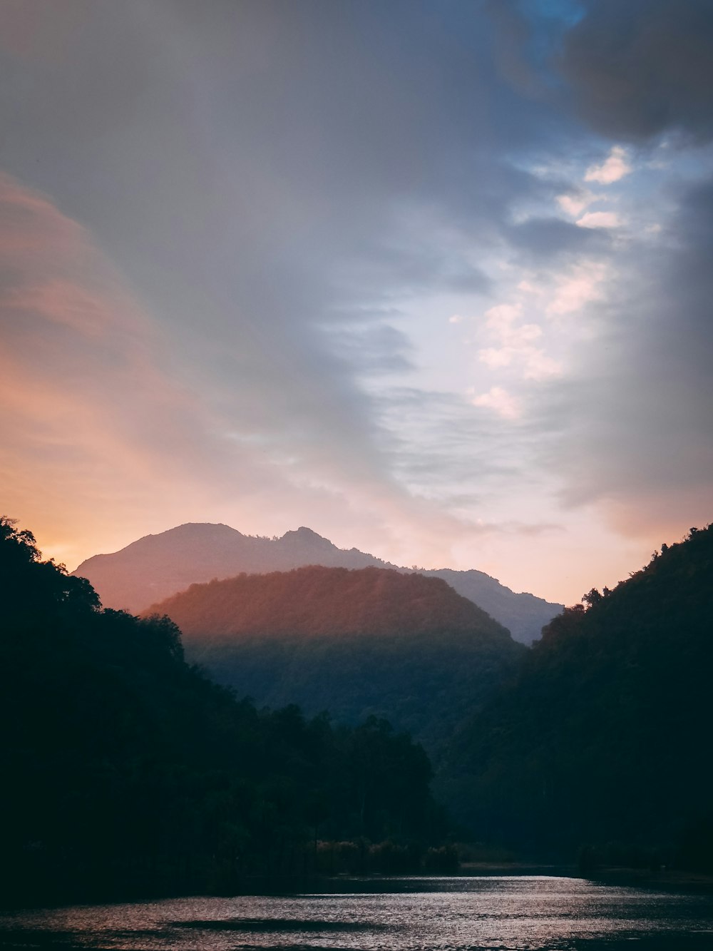 silhouette of mountains under cloudy sky during daytime