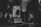 A dark, monochromatic cityscape featuring large billboard advertisements on the sides of tall buildings. The image conveys a sense of urban life with the focus on modern, graphic advertising, including a prominent light-adorned column with a silhouette of a person's profile and the text 'REWRITE TOMORROW'. Another advertisement features a person holding something to eat with the text 'MEET LCT' below.