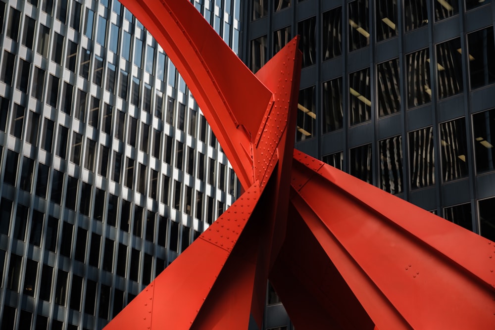 Cadre métallique rouge près d’un bâtiment en béton blanc pendant la journée