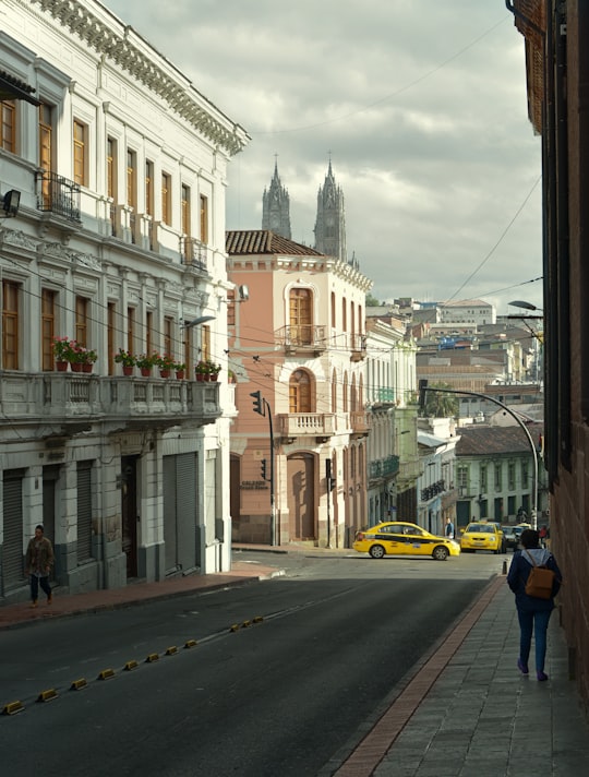 yellow car on road near white concrete building during daytime in Quito Ecuador