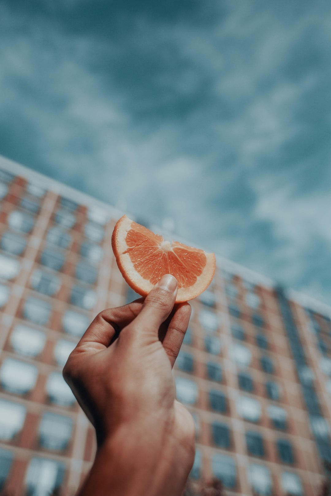 person holding orange fruit under blue sky during daytime