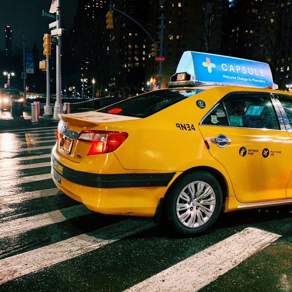 yellow taxi cab on pedestrian lane during night time