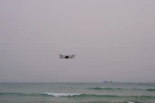 Engineers testing marine drone technology near a research pier under a cloudy sky.