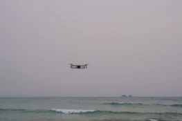 Engineers testing marine drone technology near a research pier under a cloudy sky.