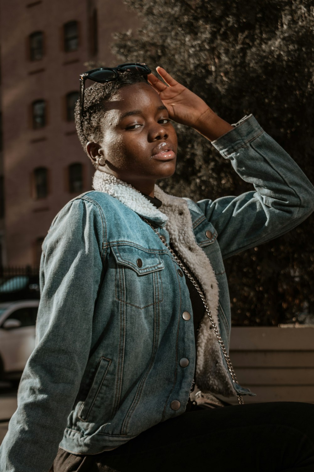 woman in blue denim jacket standing and covering her face