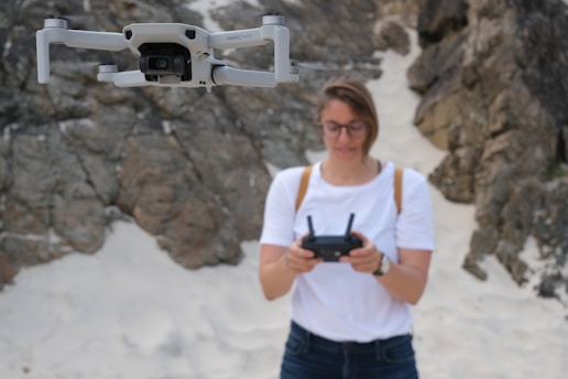 man in white crew neck t-shirt holding white and black drone
