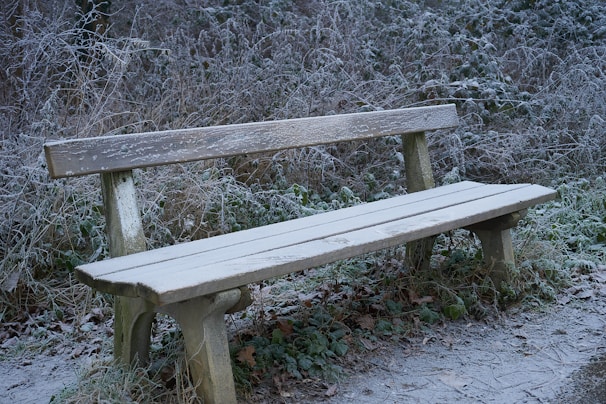 Foldable snow-resistant bench dusted with fresh snow in a cozy backyard setting.