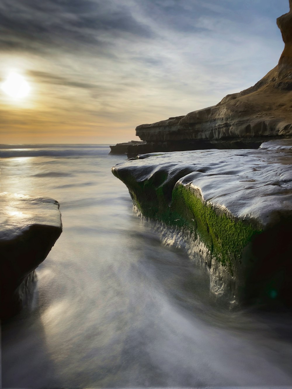 body of water near brown rock formation during daytime