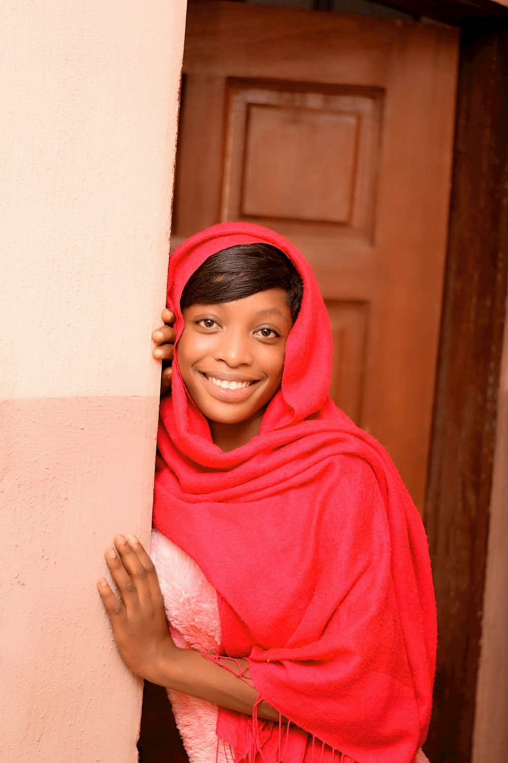 woman in red hijab leaning on white wall