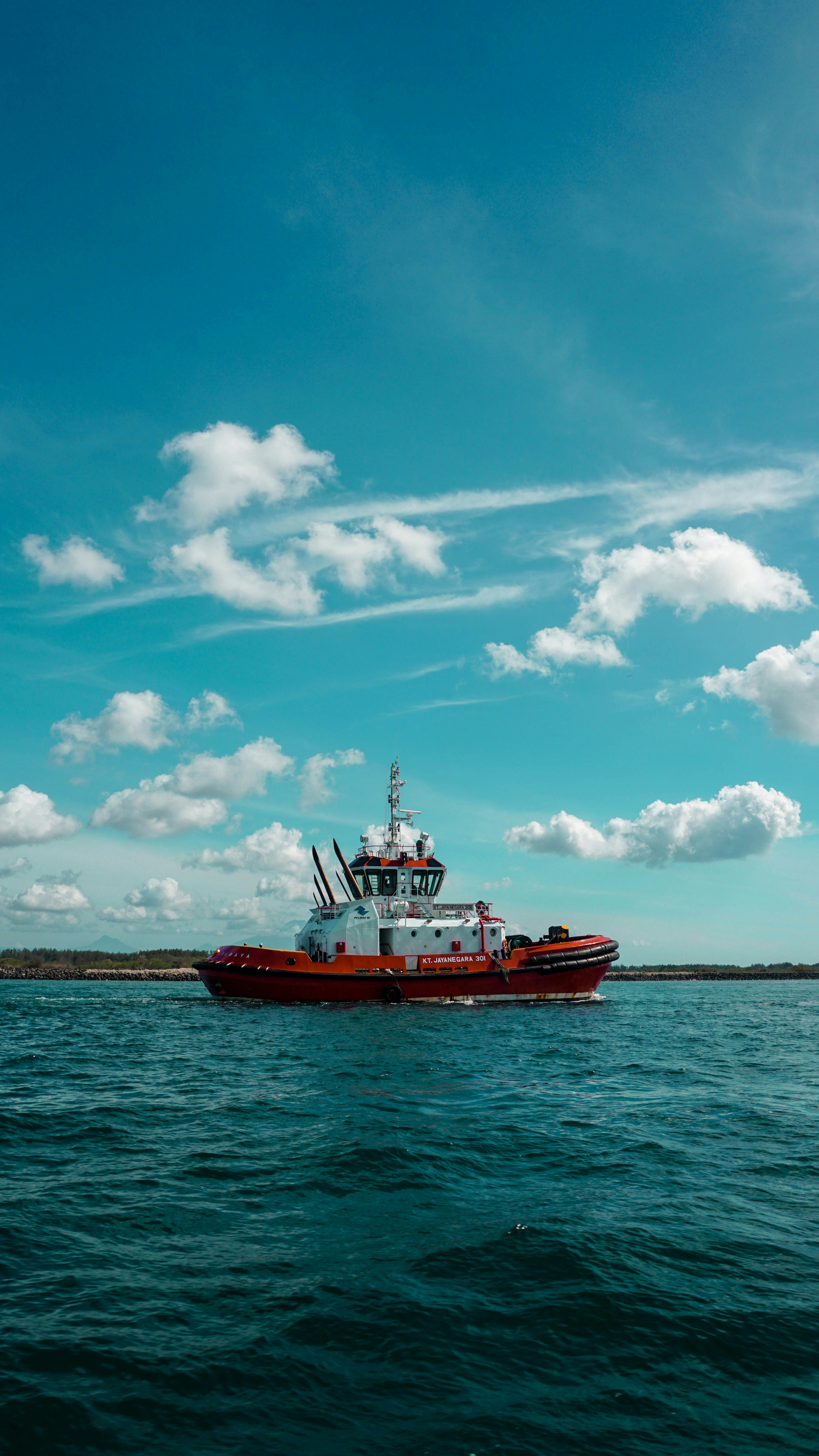 Red and white boat on sea under blue sky and white clouds during ...