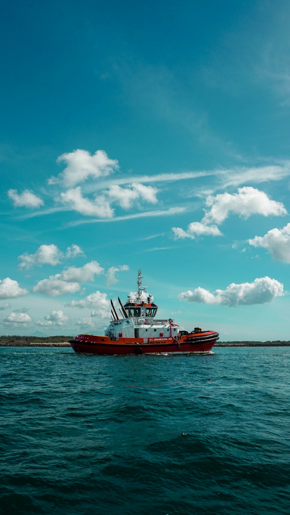 barco rojo y blanco en el mar bajo el cielo azul y las nubes blancas durante el día