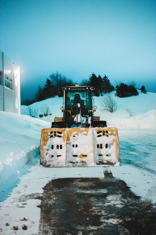 Heavy equipment clearing snow from a paved lot