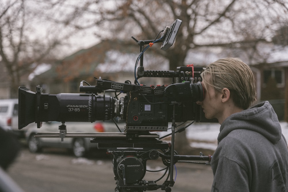 man in gray hoodie using black video camera