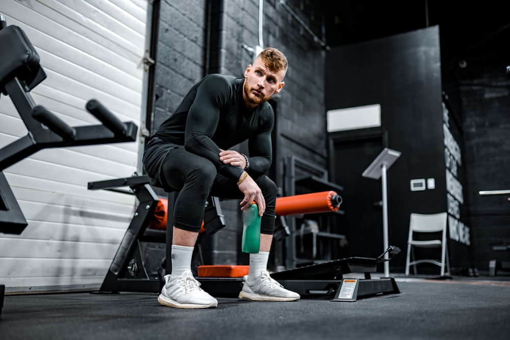 woman in black long sleeve shirt and black pants sitting on exercise equipment