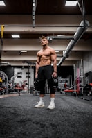 topless man in black shorts and white socks running on gray concrete floor