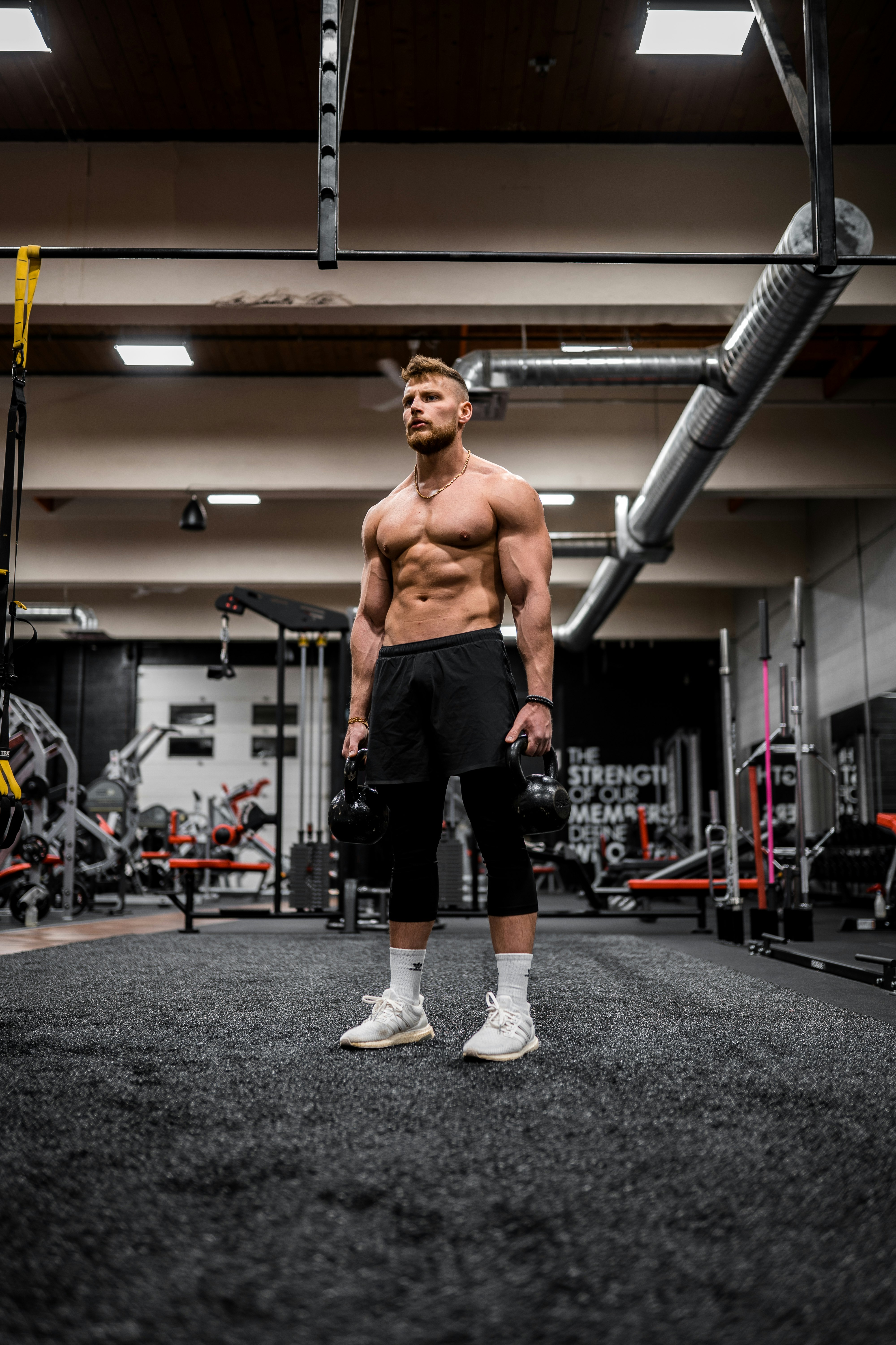 topless man in black shorts and white socks running on gray concrete floor