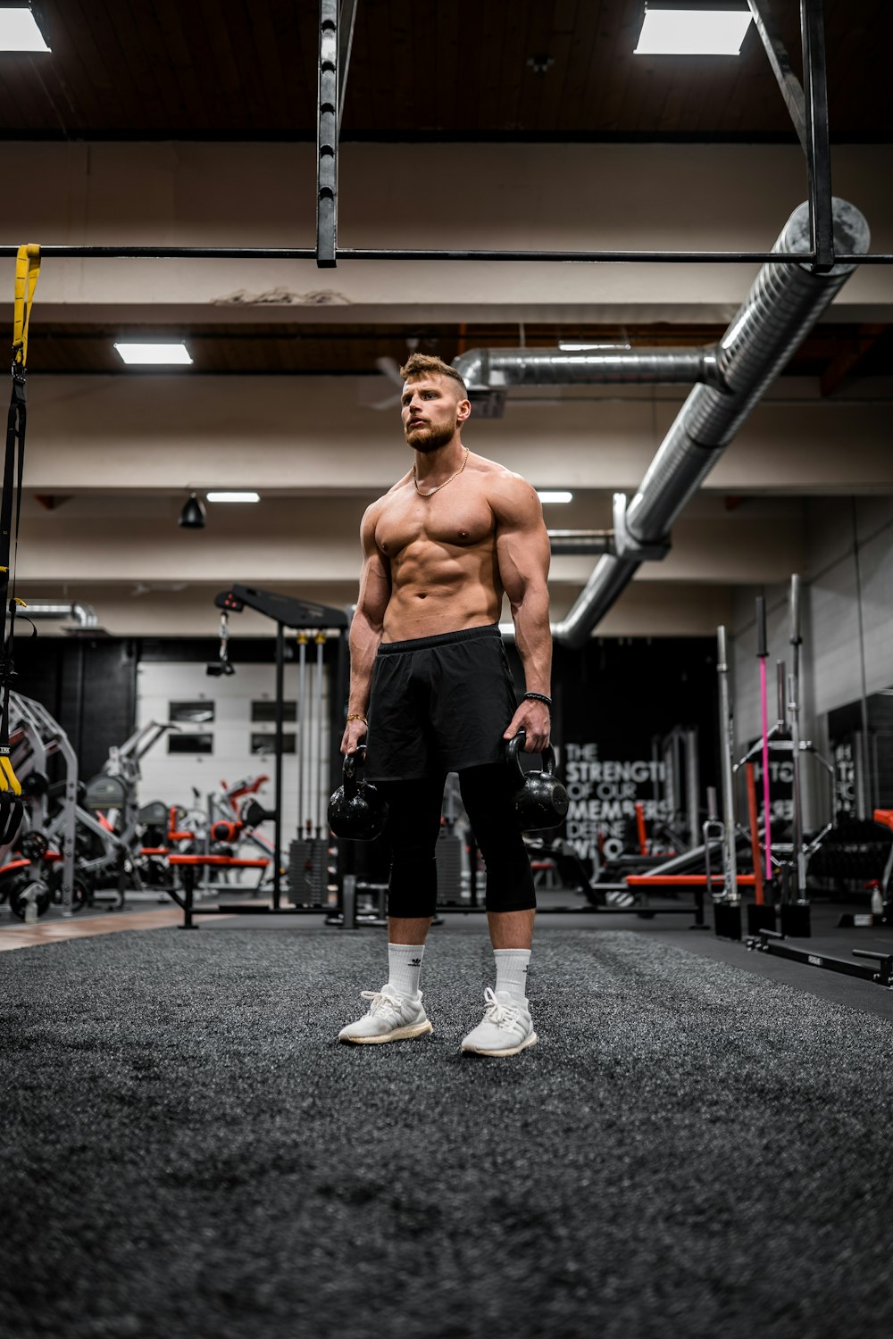 topless man in black shorts and white socks running on gray concrete floor